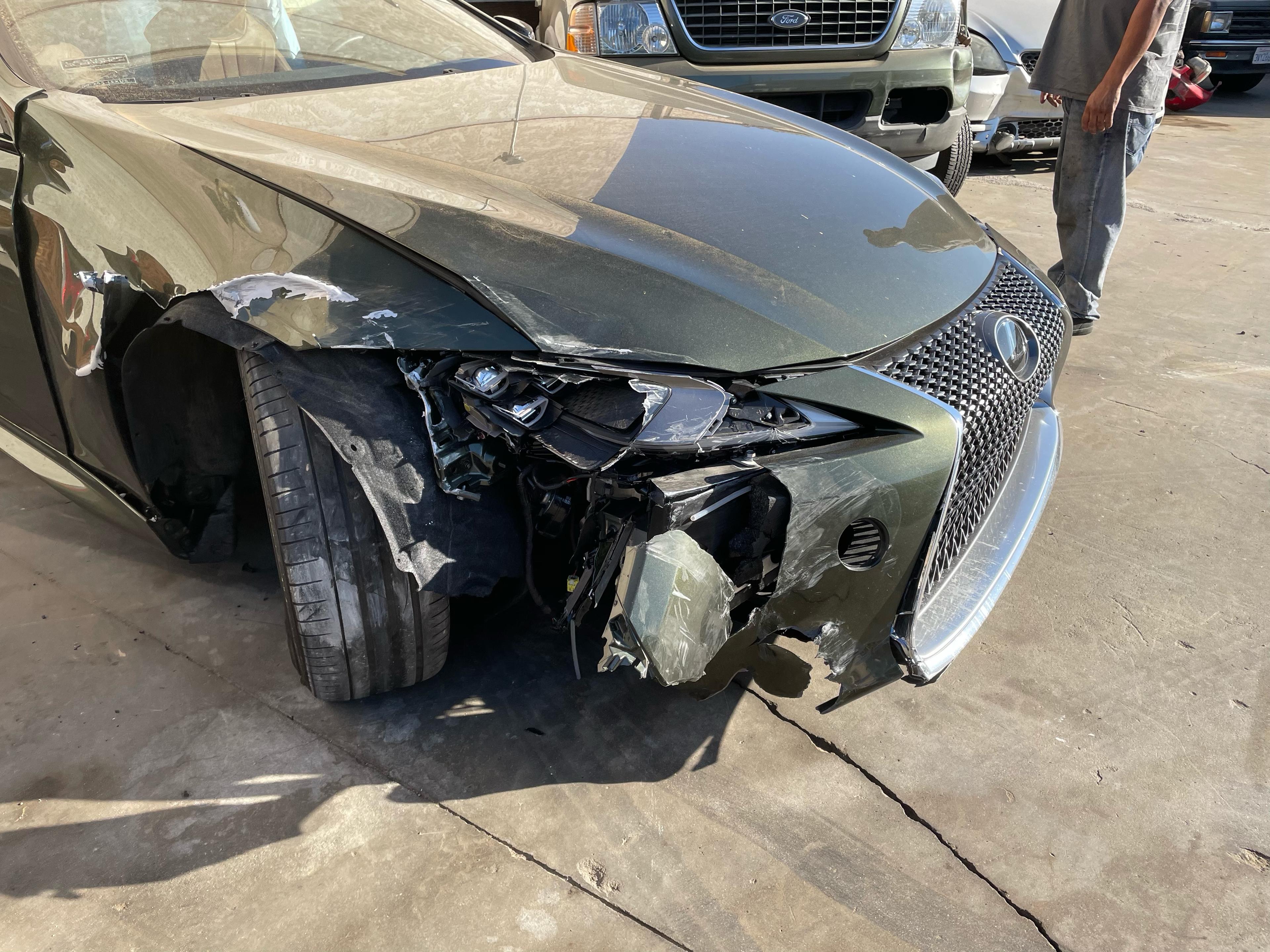 Before repair: green Lexus LC from the front driver-side angle, with damage on the front driver side