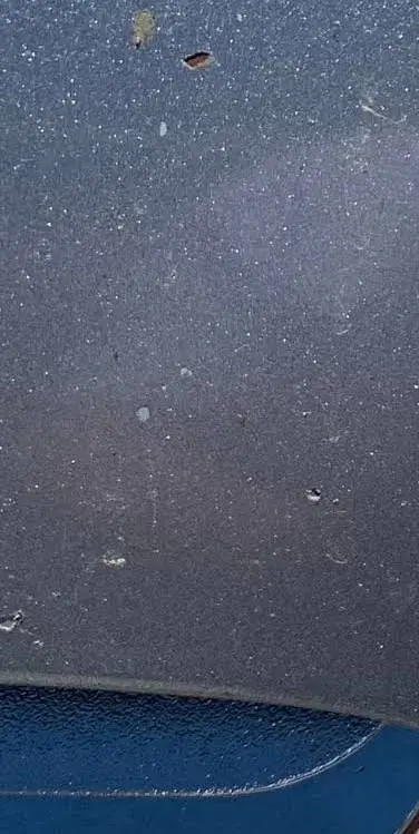 Close-up of dark vehicle paint with small firework debris marks and surface specks