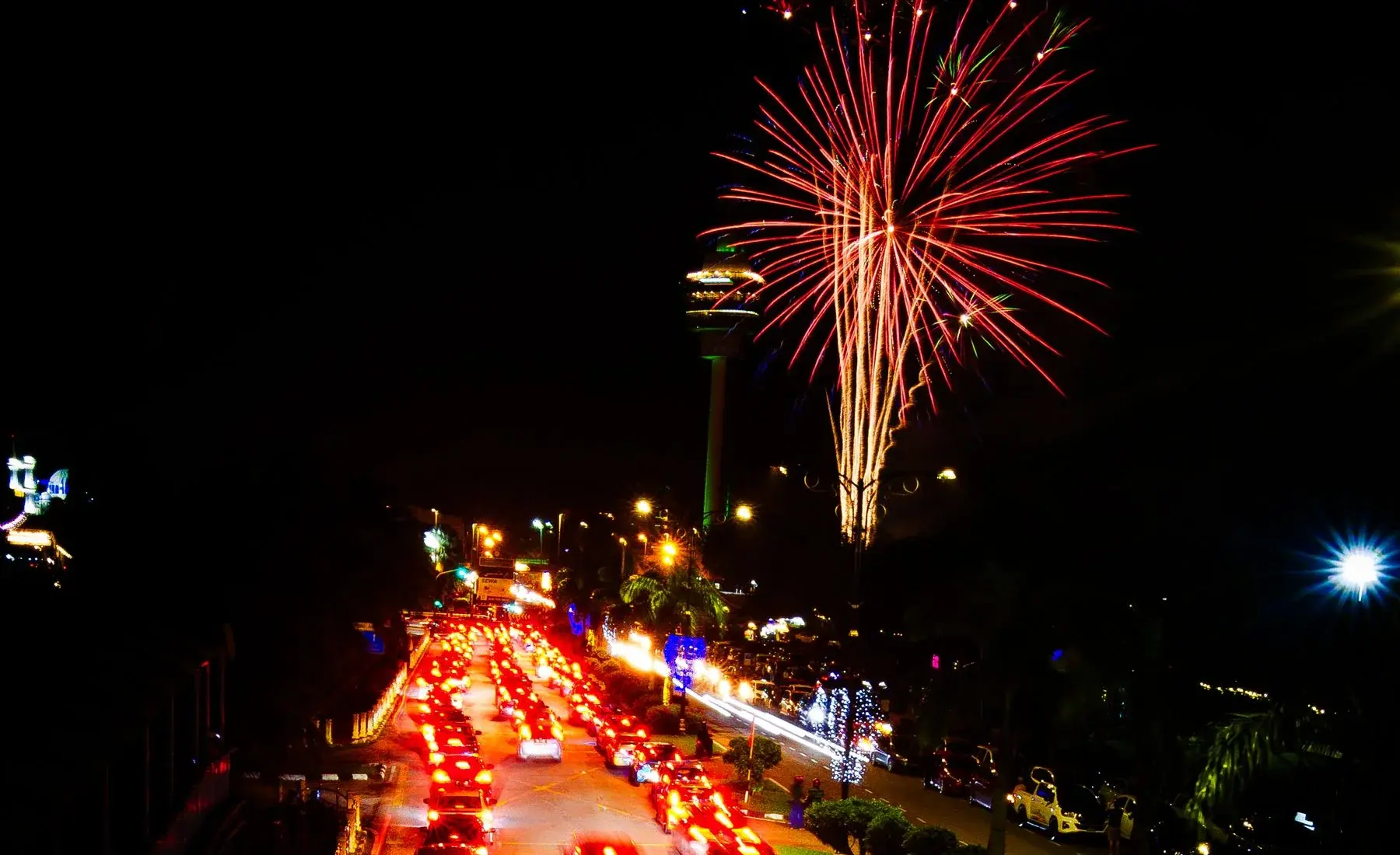 Cars on a city road under Fourth of July fireworks at night
