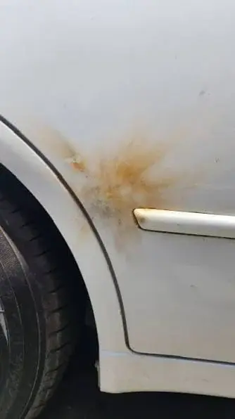 White vehicle quarter panel with orange scorch residue near the wheel arch