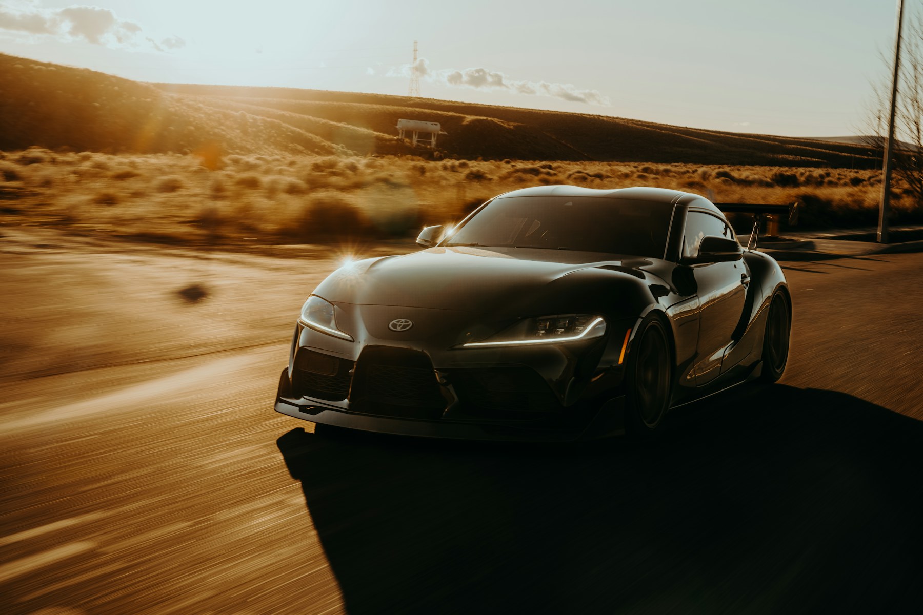 Black Toyota Supra driving at sunset